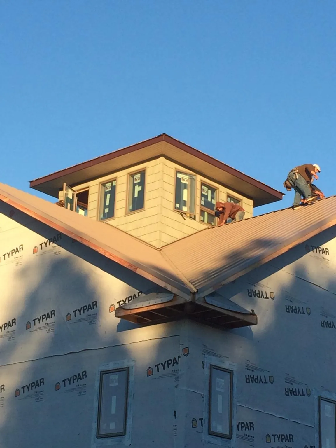 Roofers working around a rooftop cupola on a new metal roof at sunset — Roof Waterproofing in Livonia by Roofing Brothers